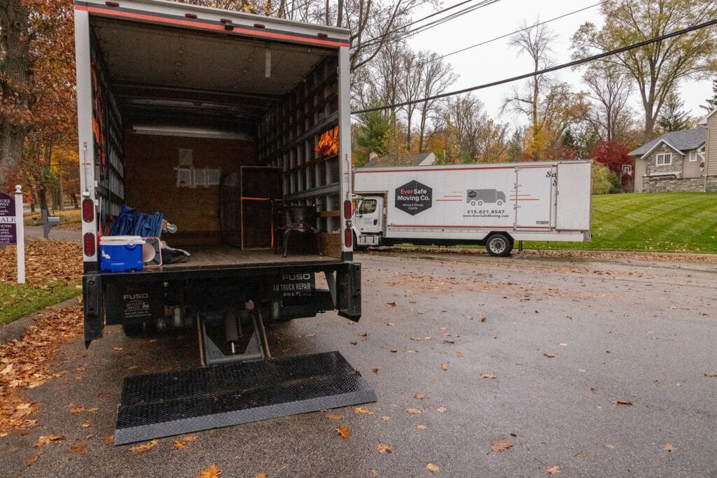 An open EverSafe Moving Co. truck sits ready for loading, with another truck parked near a home