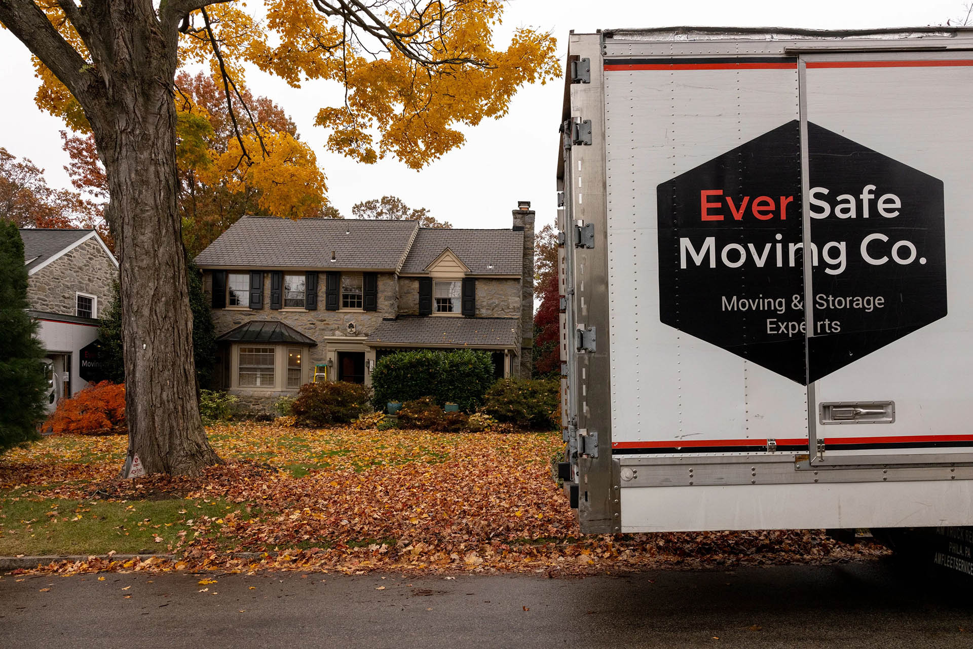 An EverSafe Moving Co. truck is stationed in front of a house surrounded by fall leaves